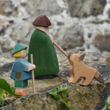 Ostheimer German shepherd wooden toy figure placed on a stone wall outdoors with a green shepherd with staff and a small boy shepherd. 