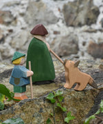 Ostheimer German shepherd wooden toy figure placed on a stone wall outdoors with a green shepherd with staff and a small boy shepherd. 