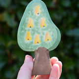 Ostheimer wooden golden pear tree scenery piece shown on the fruit side in an adult's hand. 