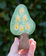 Ostheimer wooden golden pear tree scenery piece shown on the fruit side in an adult's hand. 