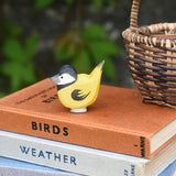 An Ostheimer bird figure placed on top of a pile of old books next t a Kraul basket.