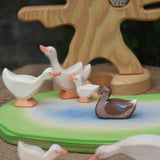 A gaggle of Ostheimer woodengeese and goslings on a wooden pond scene piece with the bird tree with an owl on the branch on the background.