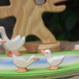 Two Ostheimer goslings placed on a wooden pond scene piece. one goslings has it's head held high and the other has it's head low.