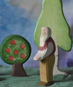 An Ostheimer grandfather wooden toy figure placed in the middle of a small world play scene. There are Ostheimer trees in the background. This wooden figure is part of a large range of expertly hand crafted, Waldorf inspired, wooden toys here at Babipur. 