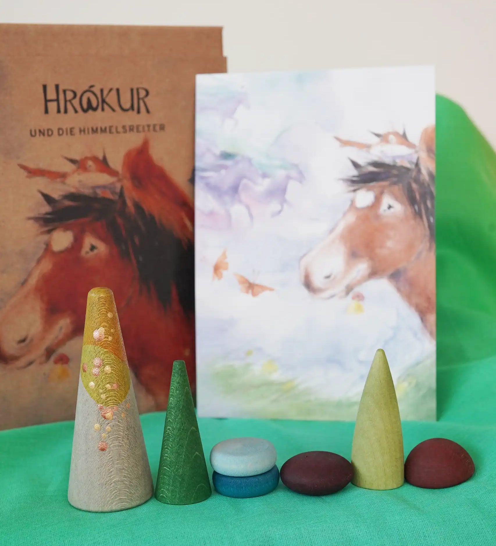 Close up of some of the pieces included in the  Grapat x Ostheimer Hrókur Mandala Pieces wooden toy set. The illustrated postcard of the horse and the box can be seen behind them in the Babipur playroom.