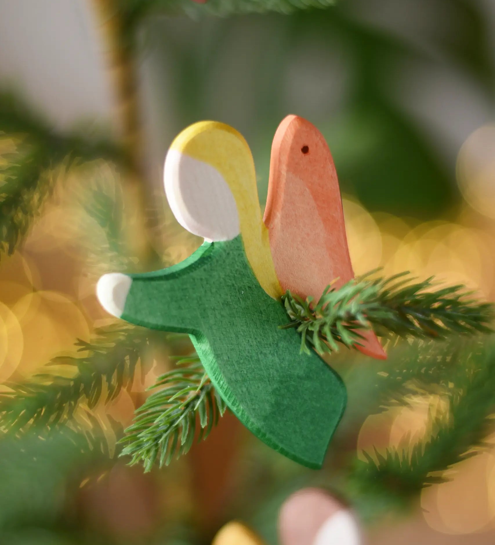 Ostheimer green angel wooden handmade decoration placed on a Christmas tree branch. 