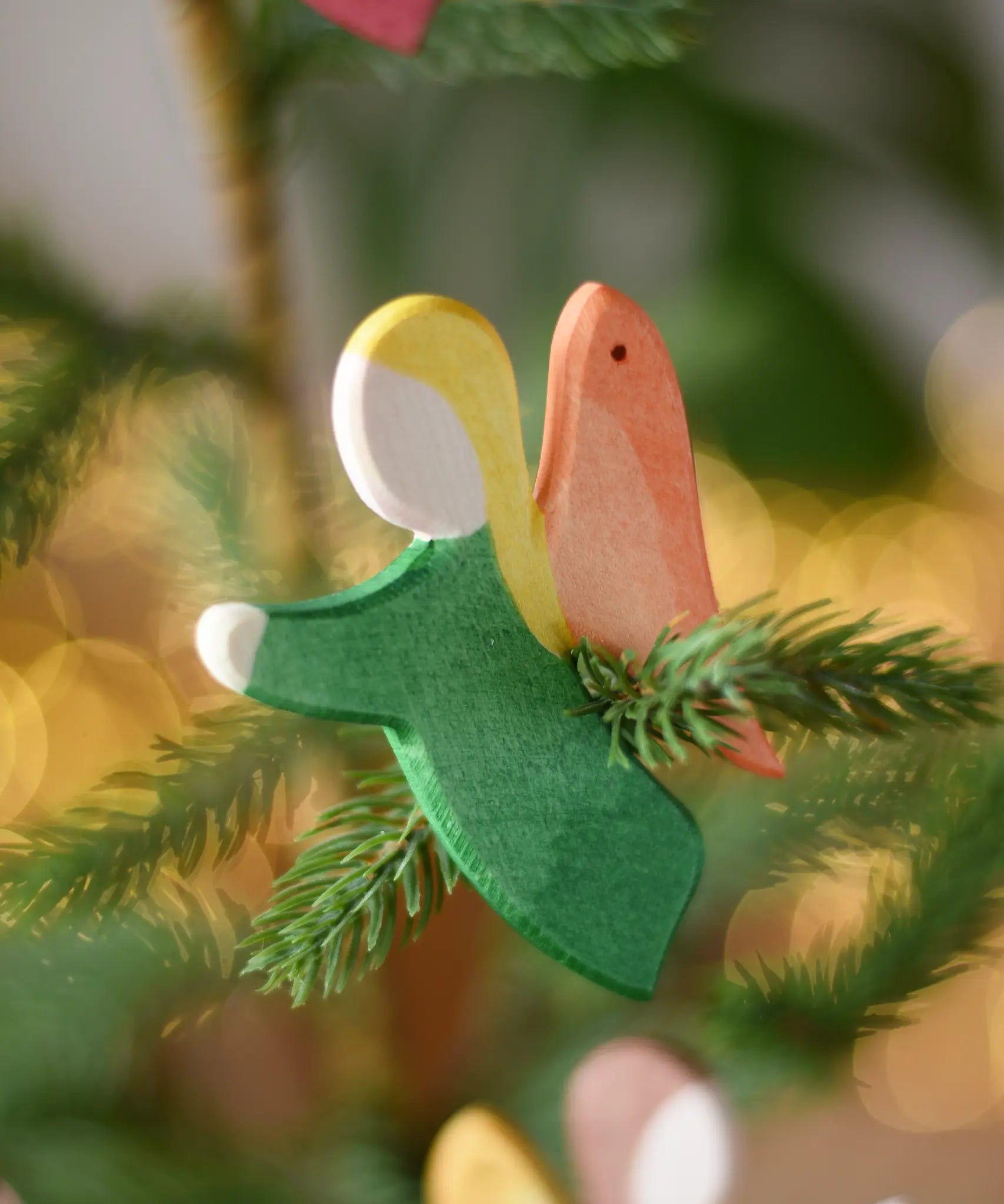 Ostheimer green angel wooden handmade decoration placed on a Christmas tree branch. 