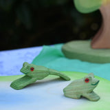 Ostheimer jumping and sitting frogs  handmade wooden toy figures placed on a pond scenery play piece. 