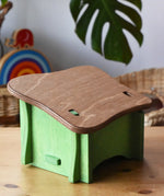 Back of the Ostheimer green hutch for toy animals placed on a wooden surface with Babipur toys in the background. 