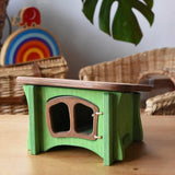 Ostheimer green hutch for toy animals placed on a wooden surface with Babipur toys in the background.
