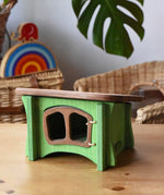 Ostheimer green hutch for toy animals placed on a wooden surface with Babipur toys in the background.