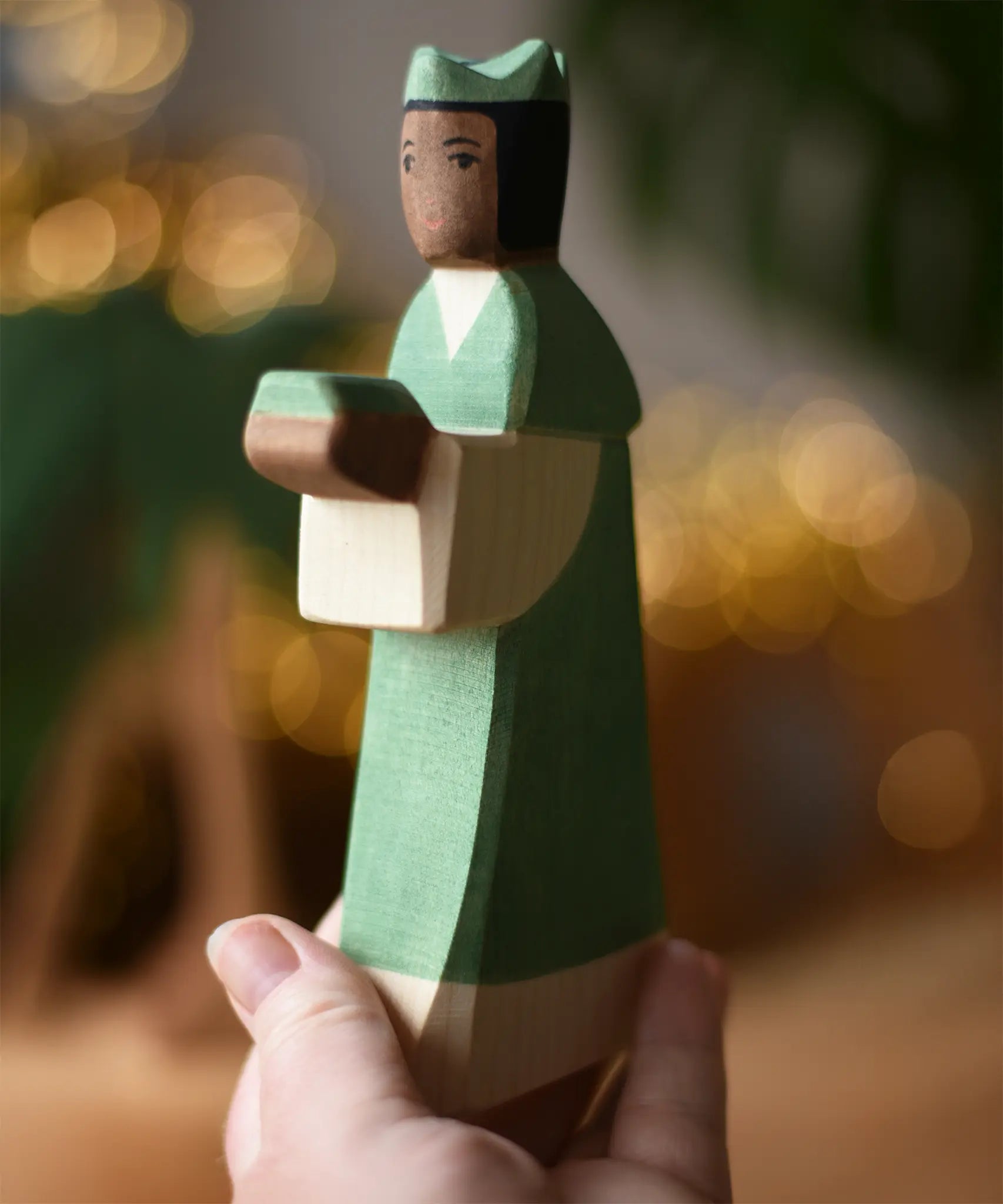 Ostheimer green king wooden toy figure in a child's hand. 