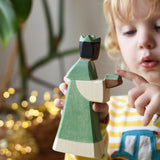 Ostheimer green king wooden toy figure in a child's hand. Child pointing at the gift in the figure's hands.