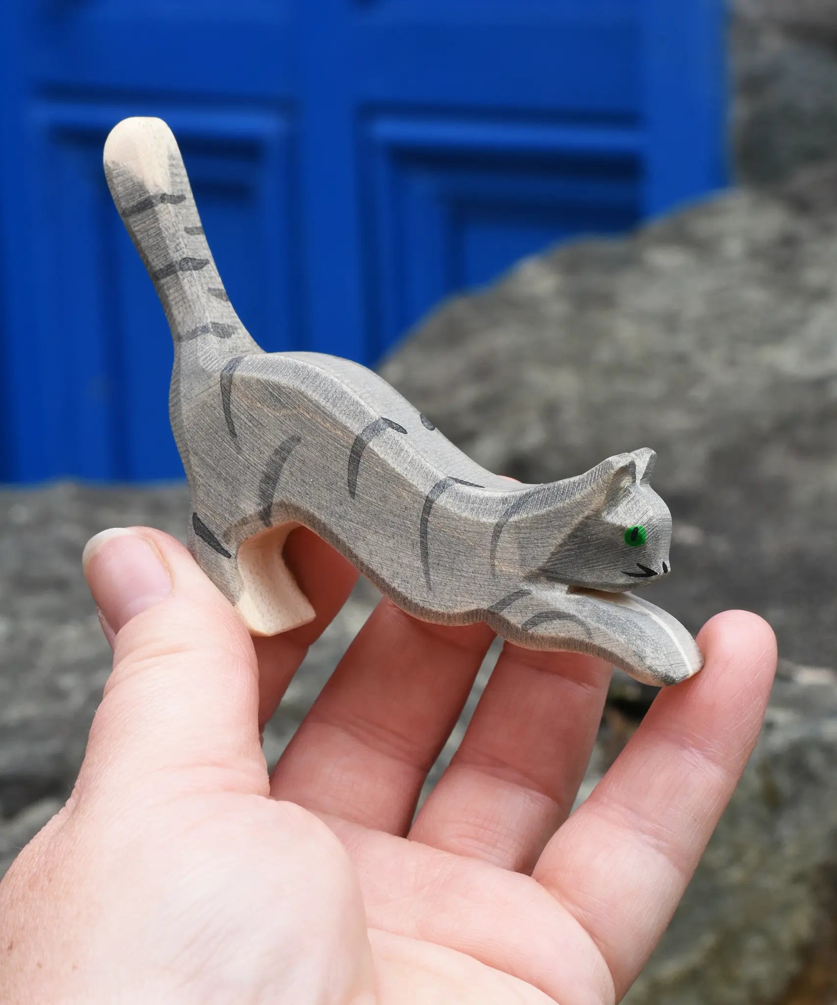 Ostheimer grey striped jumping car wooden toy figure in a child's hand.