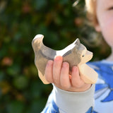 Ostheimer grey and white running sled dog wooden toy figure in a child's hand.