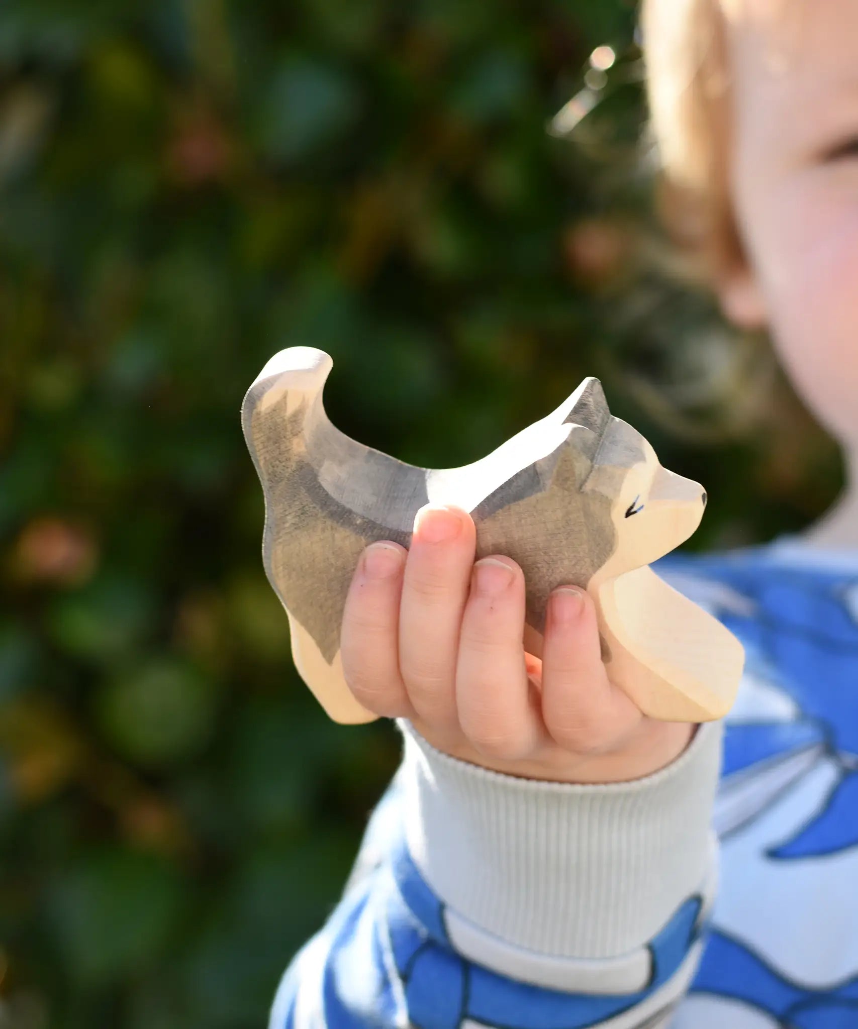 Ostheimer grey and white running sled dog wooden toy figure in a child's hand.