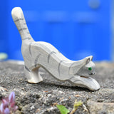 Ostheimer grey striped jumping car wooden toy figure placed on a stone wall outdoors.