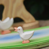 An Ostheimer gosling with it's head held high placed on a wooden pond scene piece.