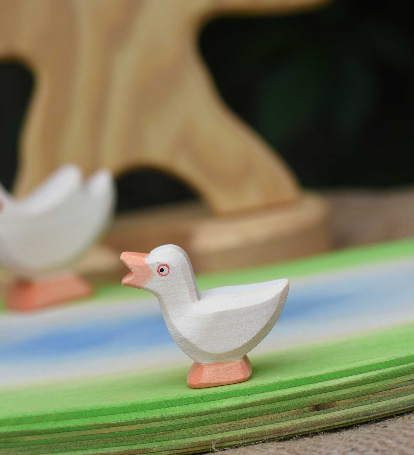 An Ostheimer gosling with it's head held high placed on a wooden pond scene piece.