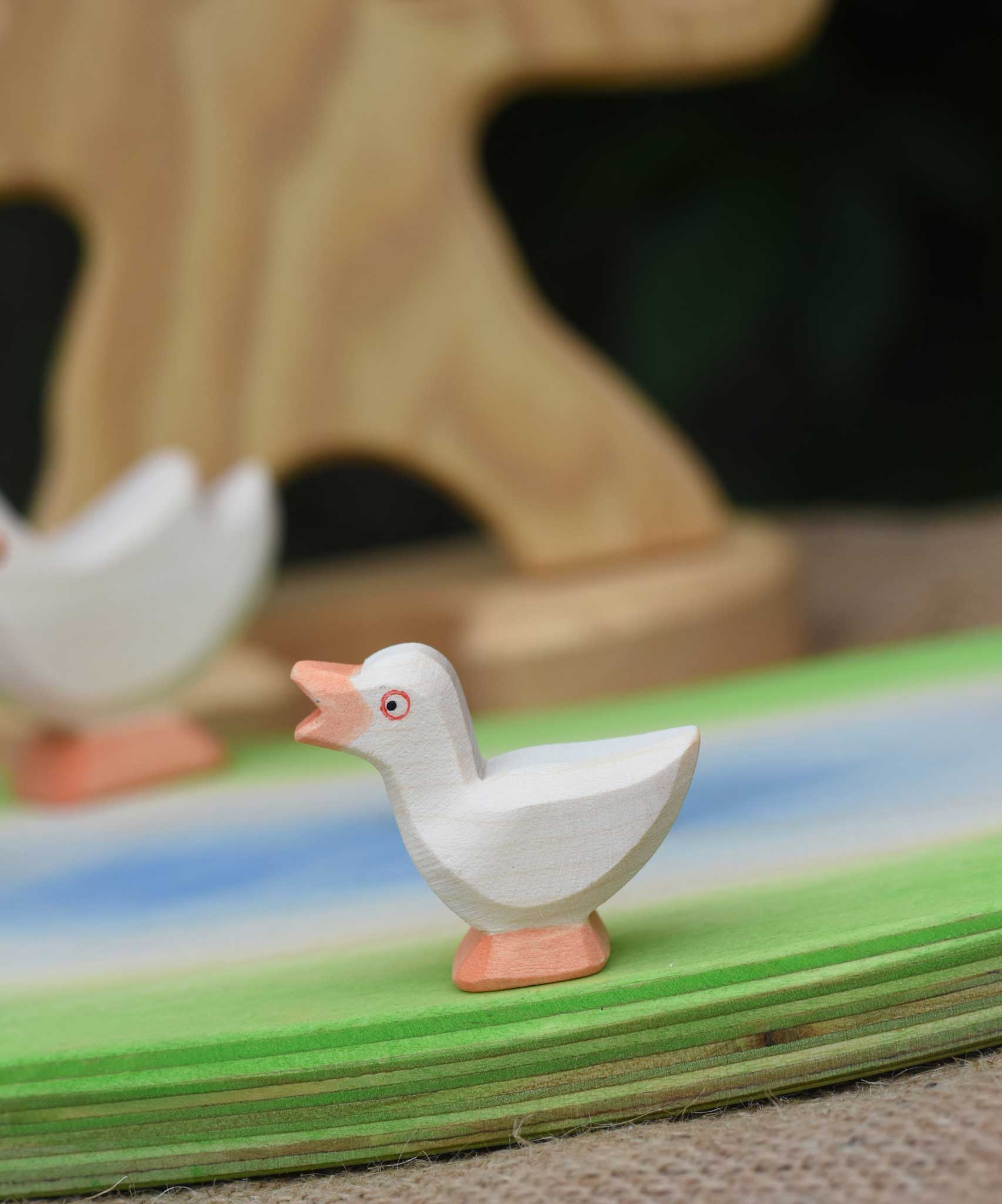An Ostheimer gosling with it's head held high placed on a wooden pond scene piece.