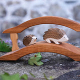 Ostheimer hedgehogs, large and small placed on a wooden bridge with a green frog underneath. Check out our full range of expertly crafted wooden toy figures and scenery here at Babipur.