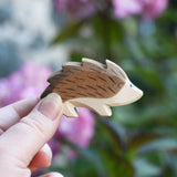 An Ostheimer wooden hedgehog figure in an adult's hand to show scale. Check out our full range of expertly crafted wooden toy figures and scenery here at Babipur.