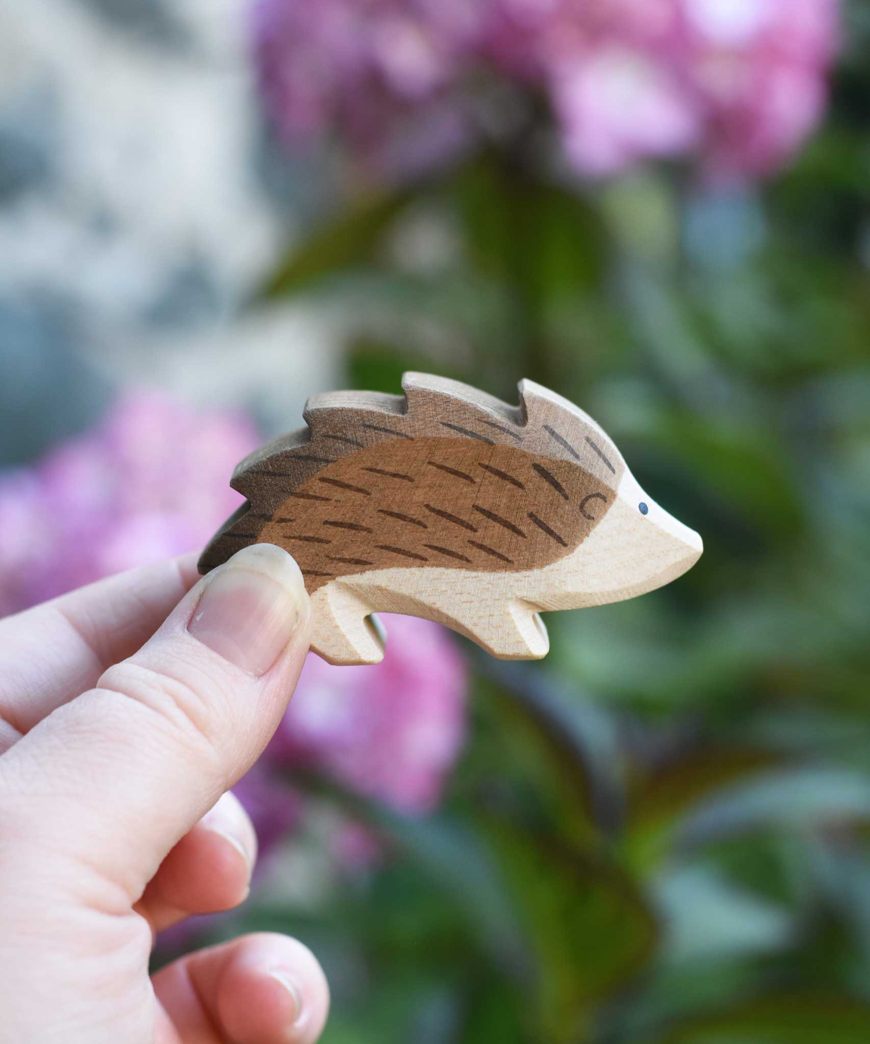 An Ostheimer wooden hedgehog figure in an adult's hand to show scale. Check out our full range of expertly crafted wooden toy figures and scenery here at Babipur.