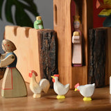 Ostheimer white hens and ochre rooster placed behind a female farmer figure holding a Kraul basket.