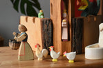 Ostheimer white hens and ochre rooster placed behind a female farmer figure holding a Kraul basket.