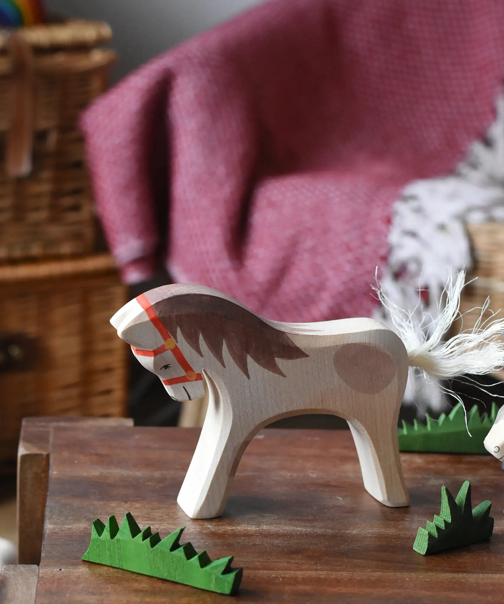 Ostheimer wooden white horse for rider toy figure placed at the front of a small world play scene with green grass scenery pieces. 