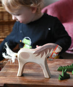 Ostheimer wooden white horse for rider toy figure placed at the front of a small world play scene with green grass scenery pieces. 