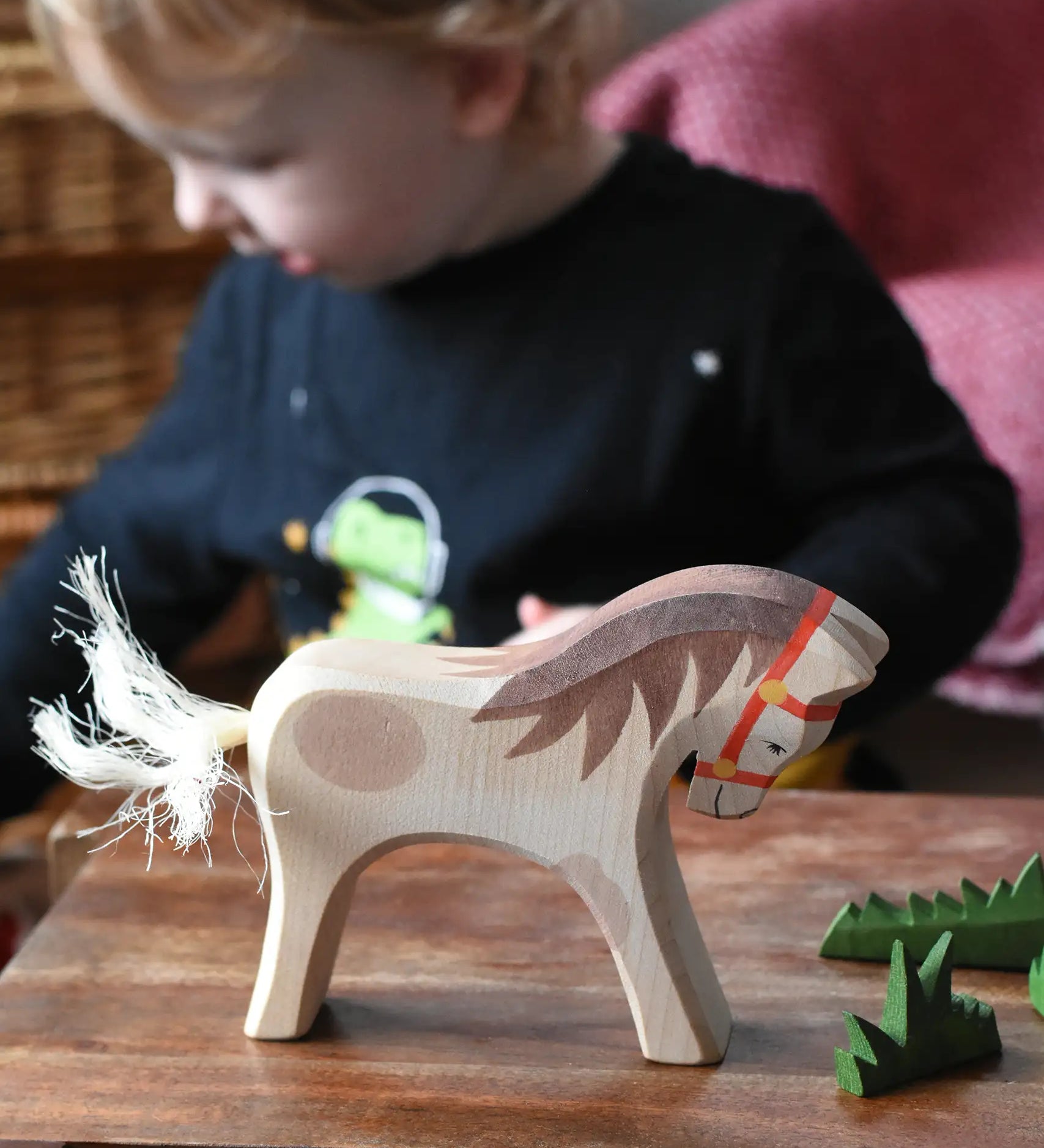 Ostheimer wooden white horse for rider toy figure placed at the front of a small world play scene with green grass scenery pieces. 