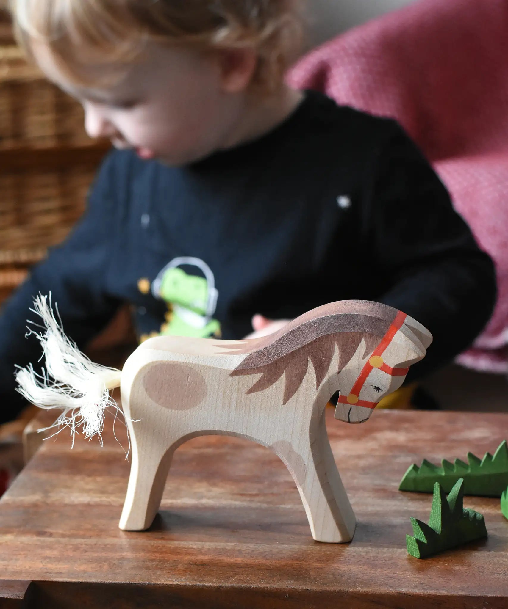 Ostheimer wooden white horse for rider toy figure placed at the front of a small world play scene with green grass scenery pieces. 