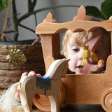 Child holding the Ostheimer wooden white horse with small blue saddle in front of the stage coach.