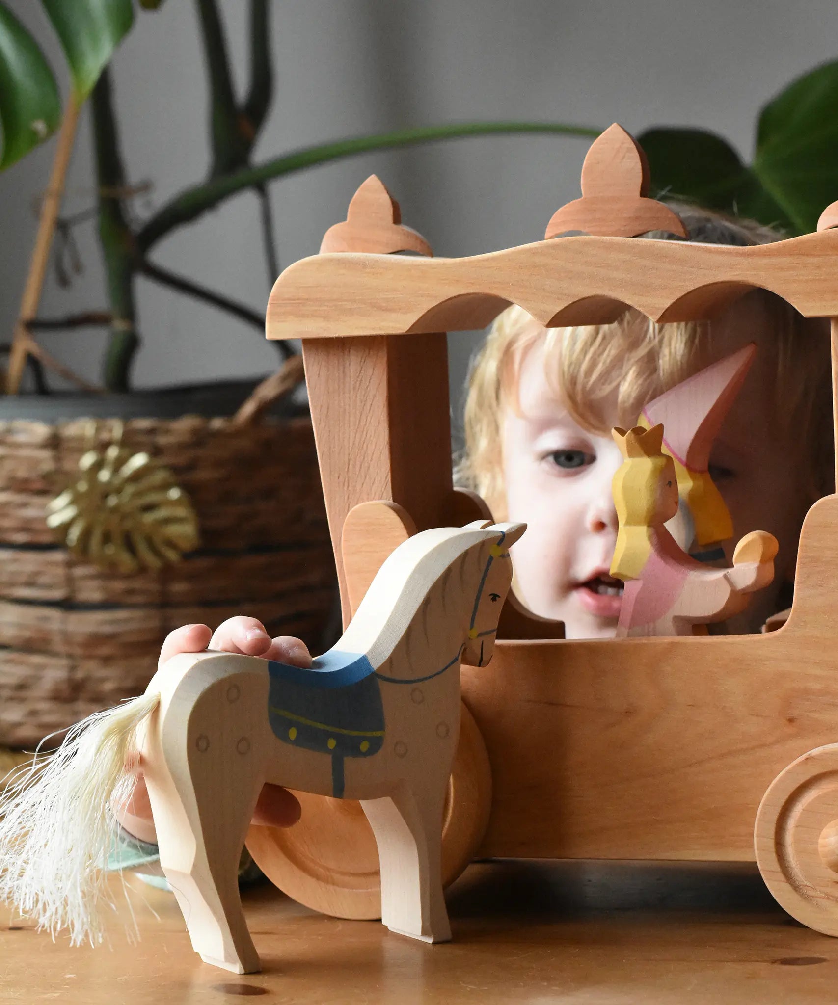 Child holding the Ostheimer wooden white horse with small blue saddle in front of the stage coach.
