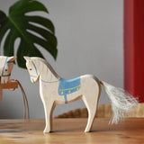 Ostheimer wooden white horse with small blue saddle placed on a wooden surface.