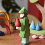 Ostheimer hunter wooden toy figure person with a green outfit with a red fire drop Grapat mandala piece balance on it's hands. 