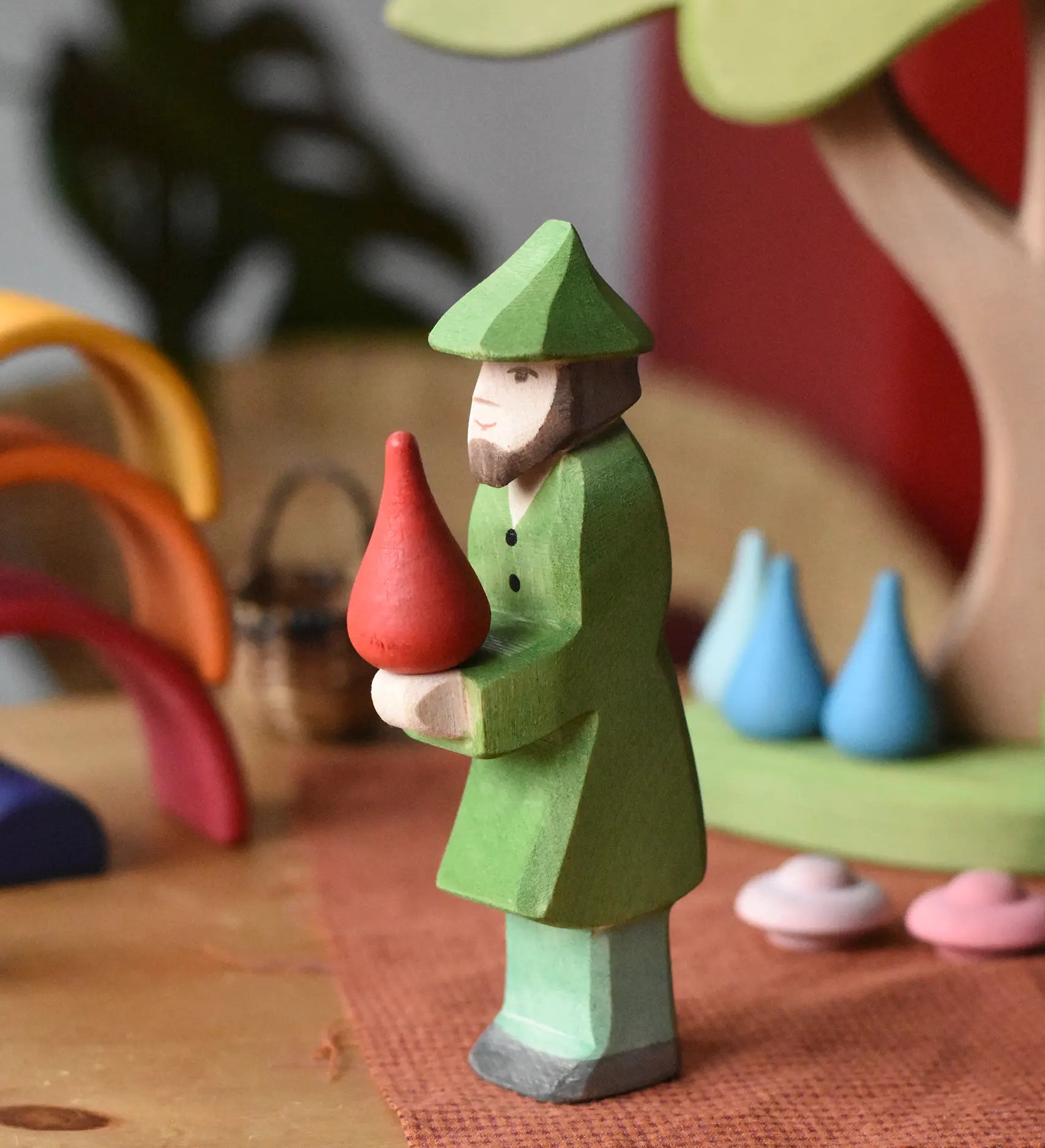 Ostheimer hunter wooden toy figure person with a green outfit with a red fire drop Grapat mandala piece balance on it's hands. 