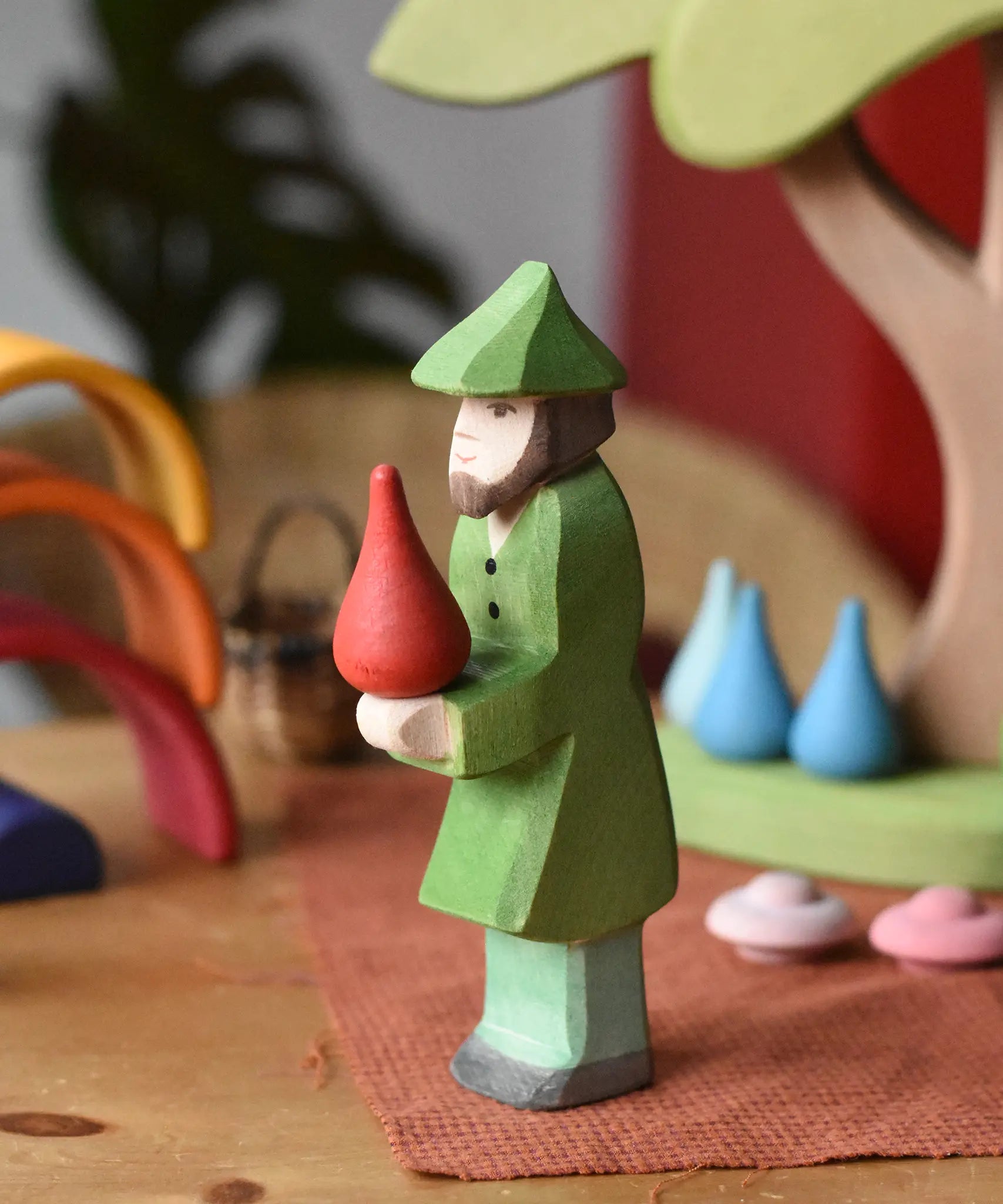 Ostheimer hunter wooden toy figure person with a green outfit with a red fire drop Grapat mandala piece balance on it's hands. 