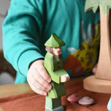 Ostheimer hunter wooden toy figure in a child's hand in a small world play scene. 