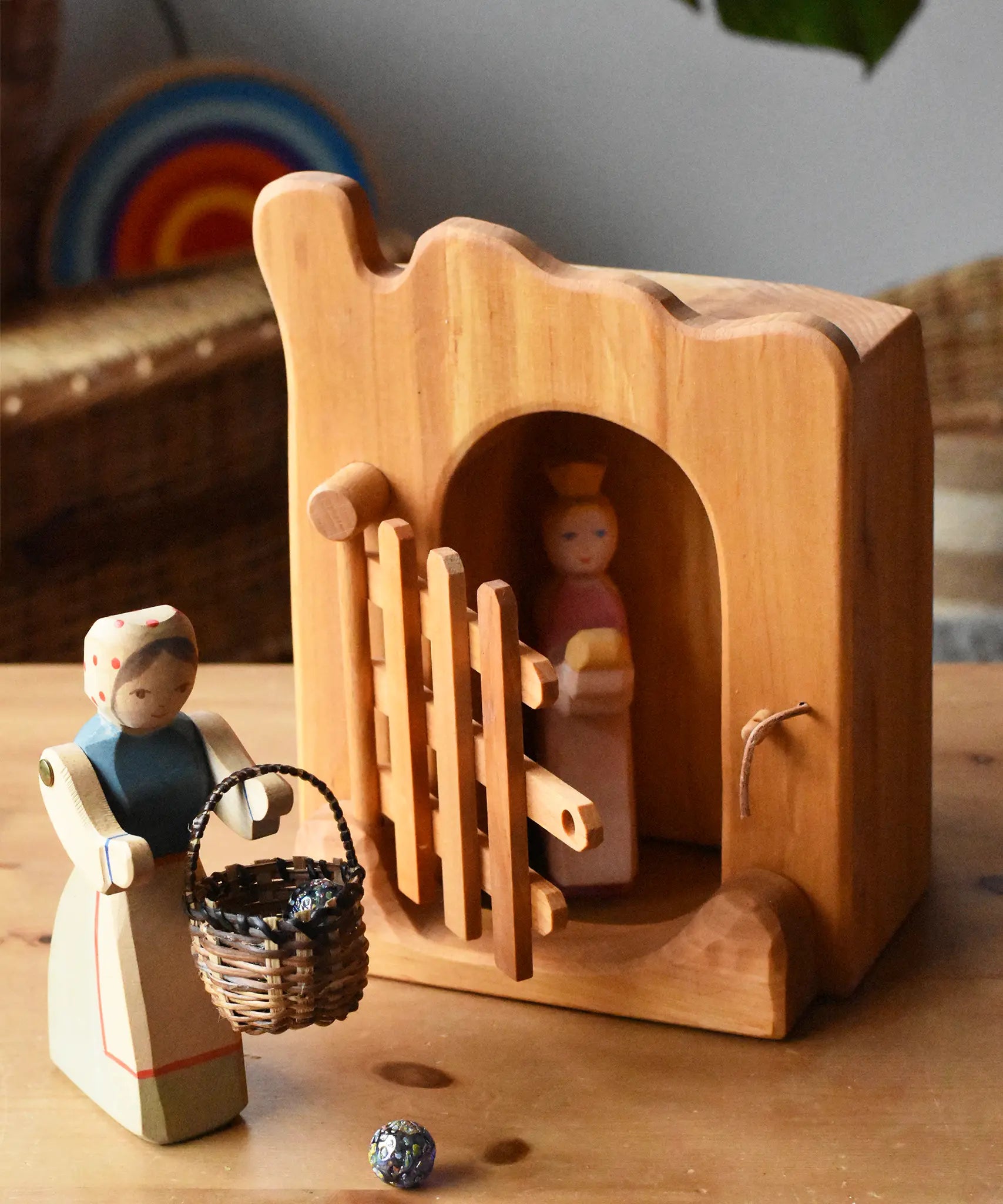 Ostheimer jailhouse wooden toy in a small world play scene with a princess figure placed inside and a female farmer placed outside with a Kraul basket filled with Billes sparkly marbles. 