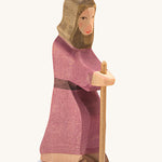A Joseph wooden figure wearing a purple robe holding a wooden staff on a cream background