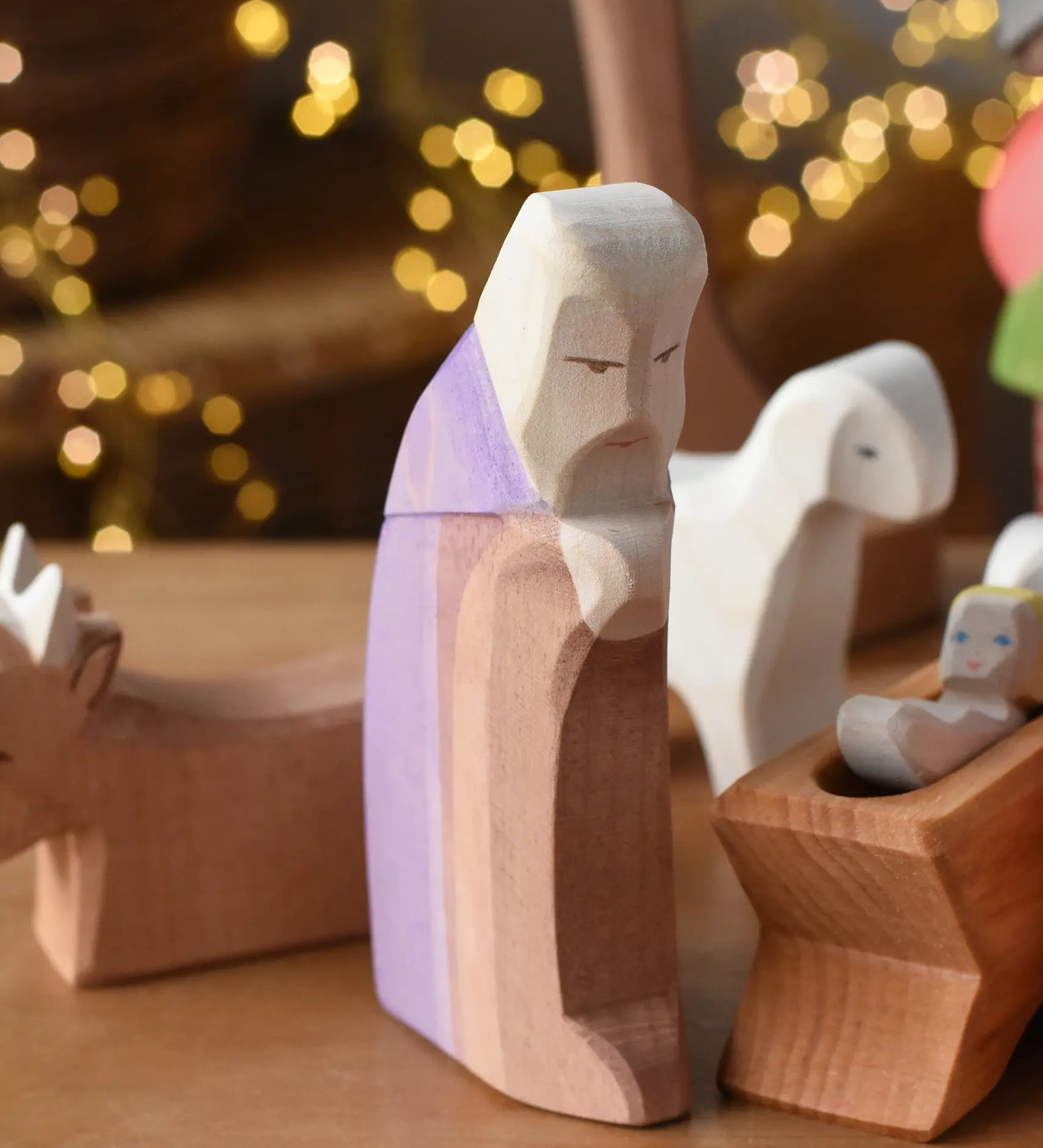 Ostheimer Joseph handmade wooden toy figure placed in the front of a small world nativity themed play scene. 