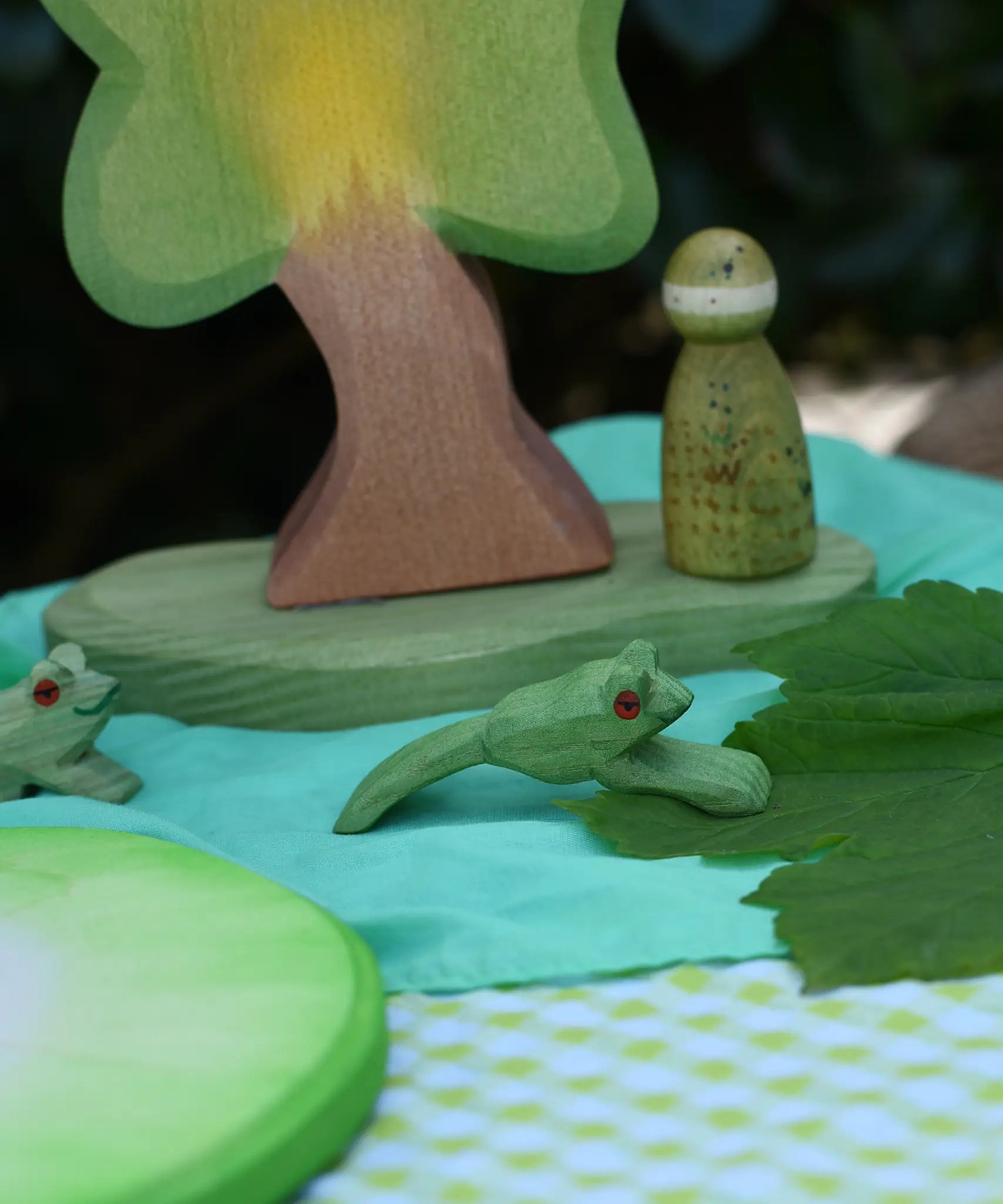 Ostheimer jumping frog handmade wooden toy figure placed in a small world play scene with other wooden toys from Ostheimer and Grapat.