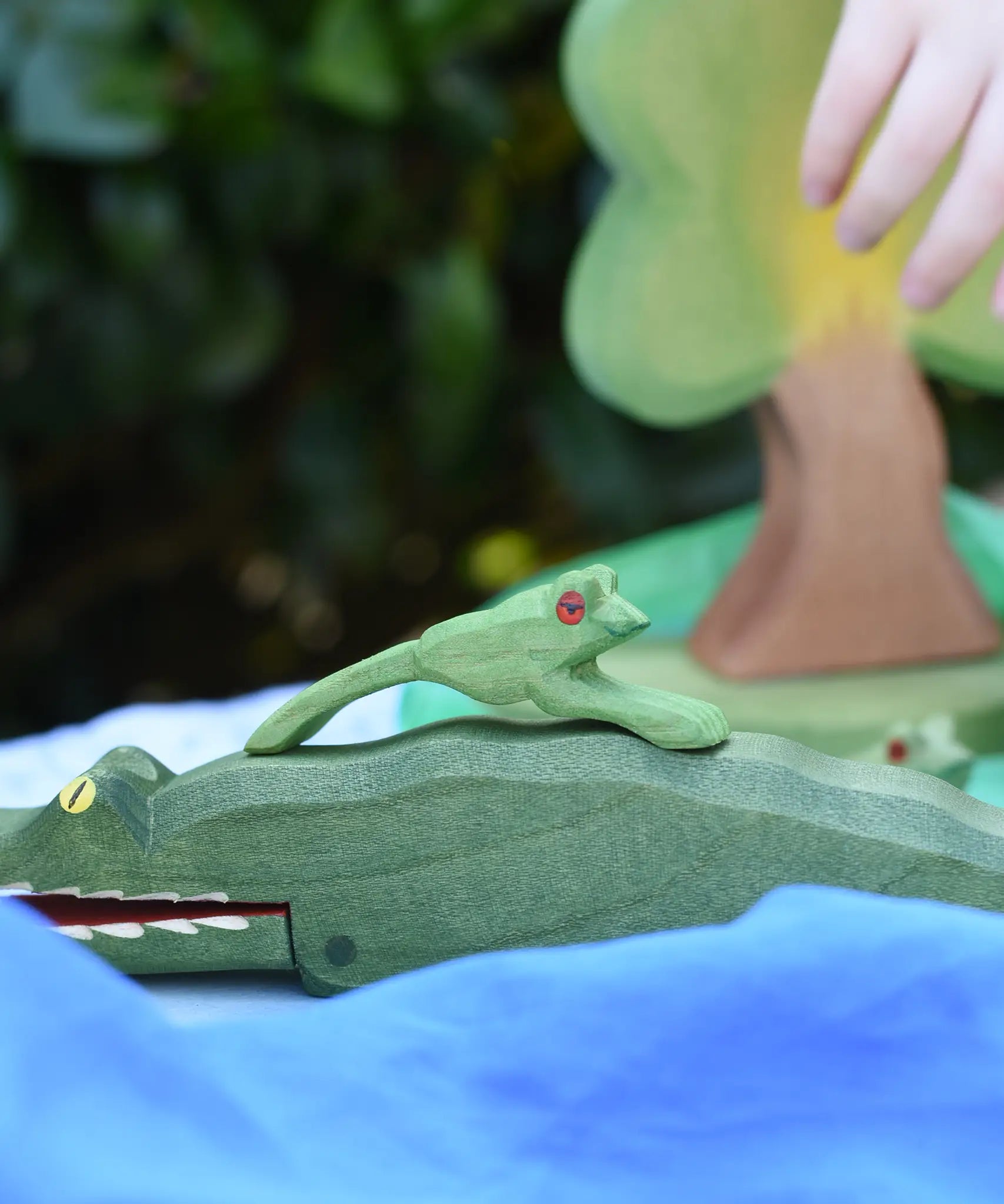Ostheimer jumping frog handmade wooden toy figure placed on the back of a crocodile.