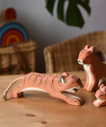 Ostheimer jumping tiger wooden toy figure placed on a wooden surface.