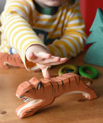 Ostheimer jumping tiger wooden toy figure with a child's hand reaching for it.