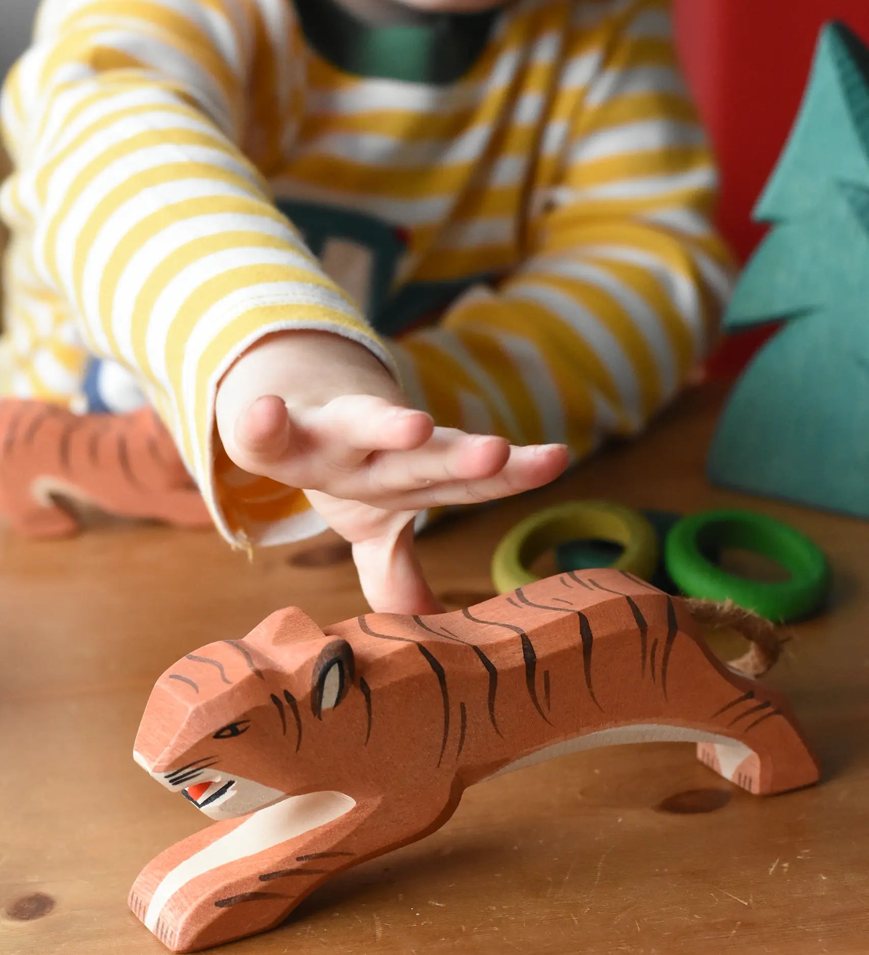 Ostheimer jumping tiger wooden toy figure with a child's hand reaching for it.