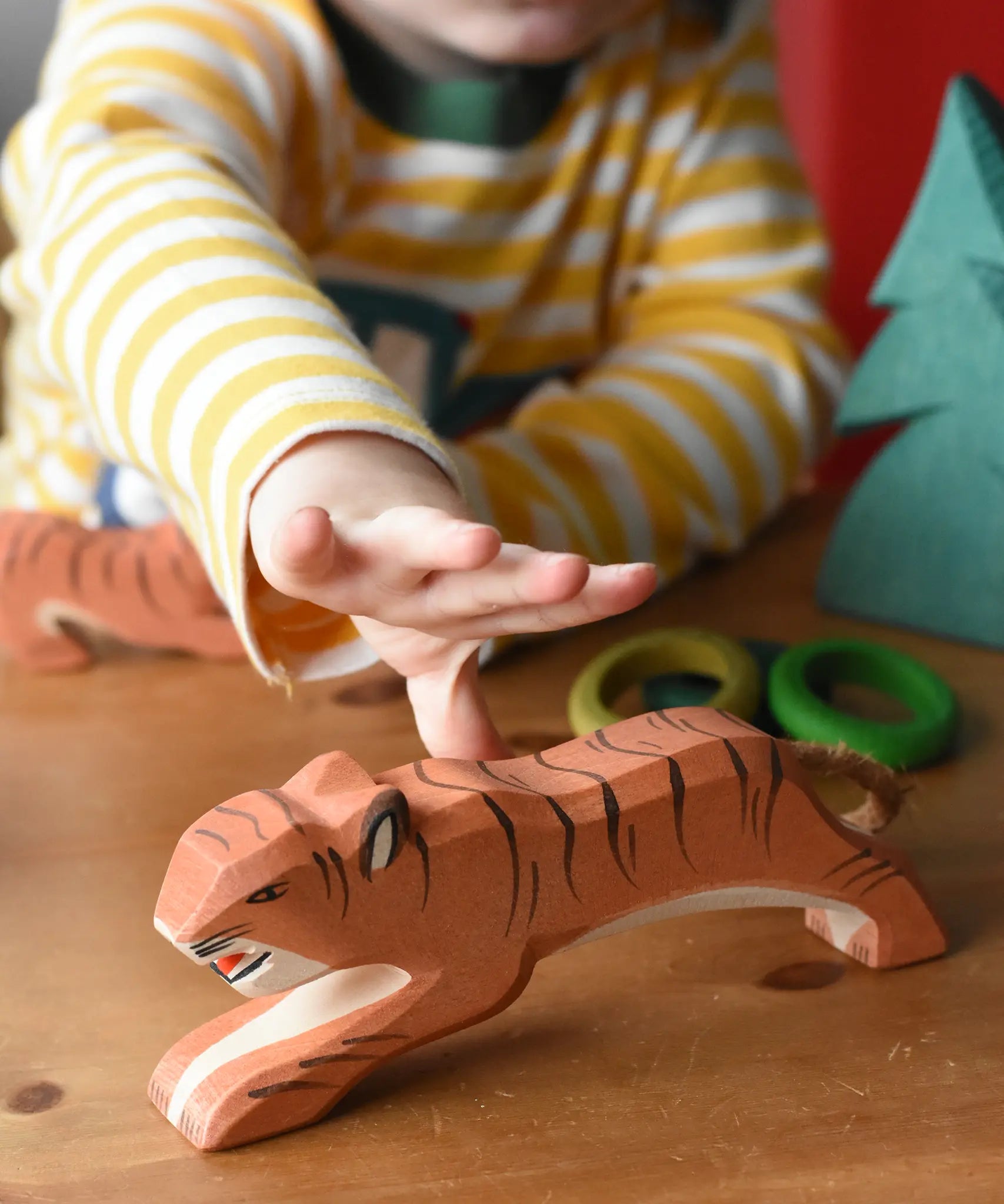 Ostheimer jumping tiger wooden toy figure with a child's hand reaching for it.