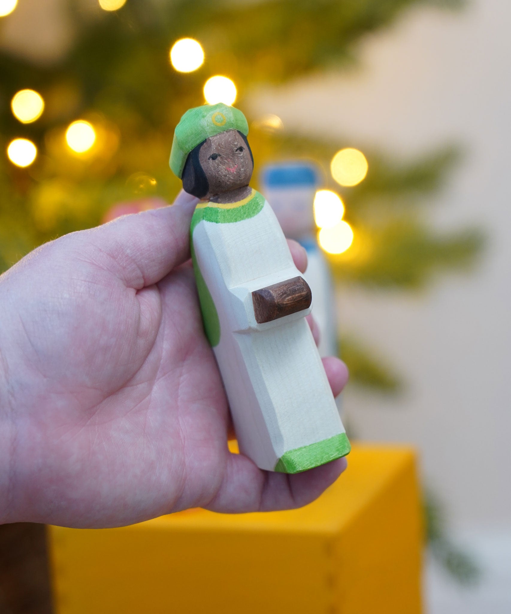 The Ostheimer Green King's Page  Three Wise Men Wooden Nativity Figure in an adult's hand. These wooden figures are part of a wide range of expertly hand crafted wooden toys here at Babipur. 